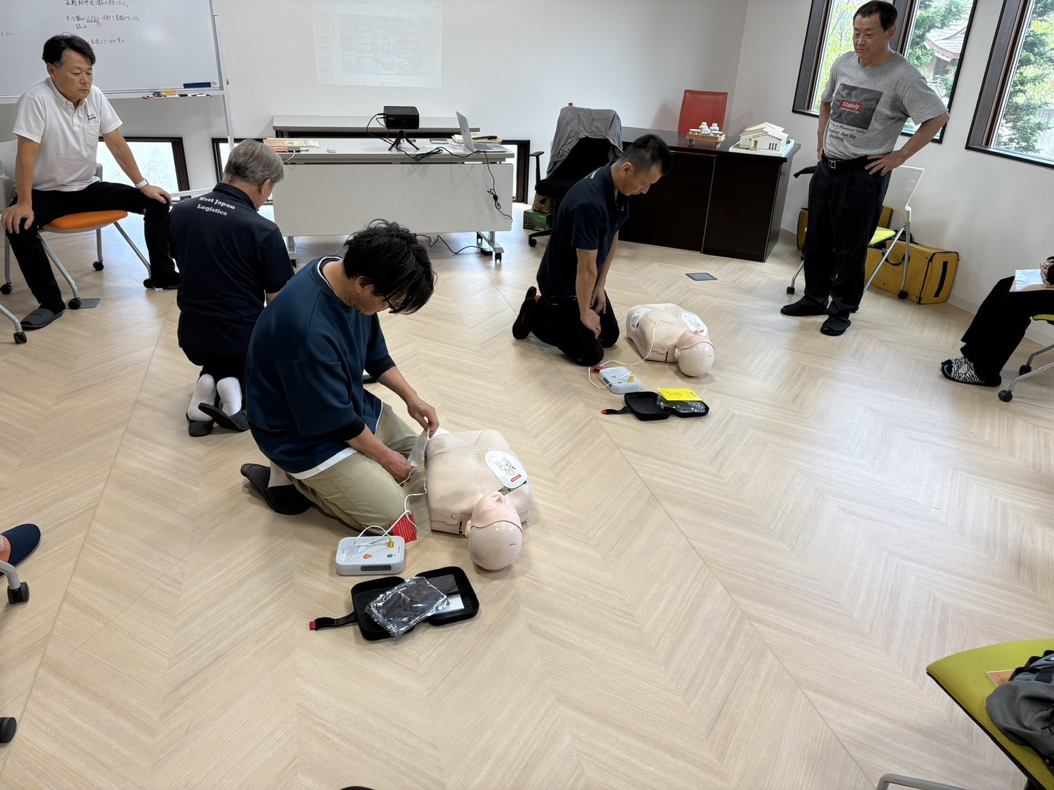 訓練用人形とAEDトレーナーを使う救命講習の実習風景